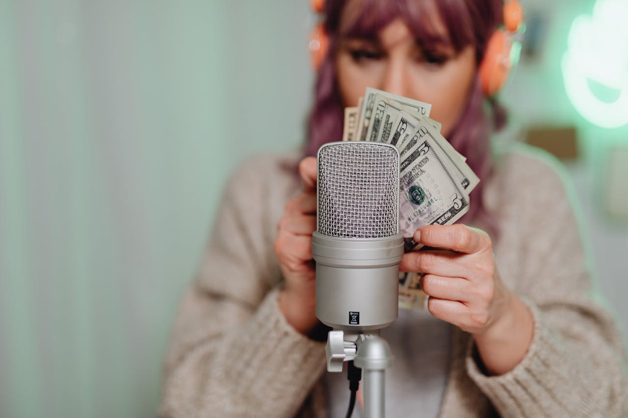 Adult woman with headset counting dollar bills in front of microphone indoors.